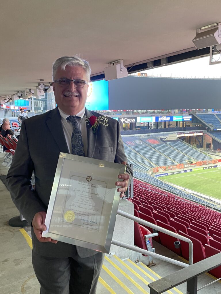 George Grossomanides at Gillette Stadium holding his Laity Award from the Greek Orthodox Metropolis of Boston